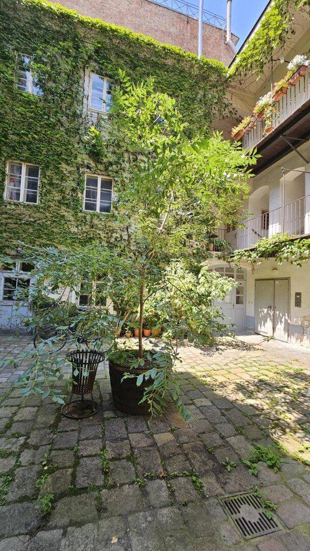 Weitläufiger Innenhof mit üppigem Grün und Blick auf die oberen Etagen mit Balkonen.
