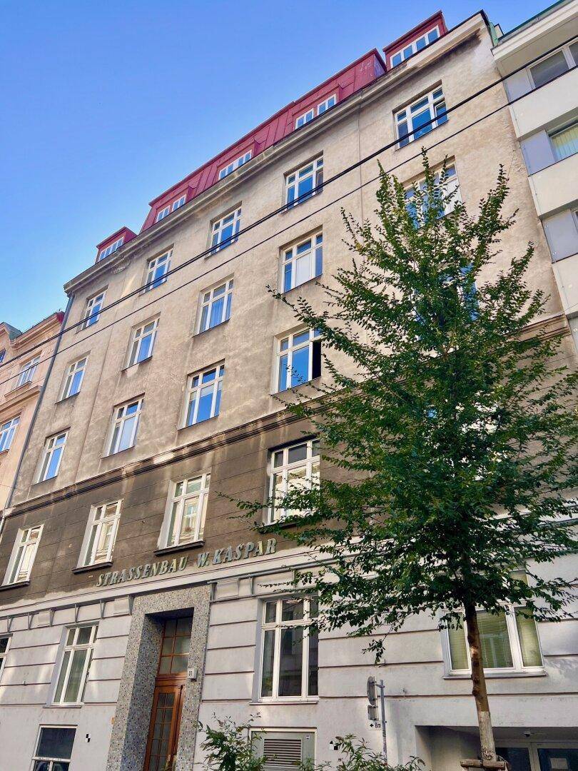 Historische Fassade eines Altbaus mit vielen Fenstern und rotem Satteldach.