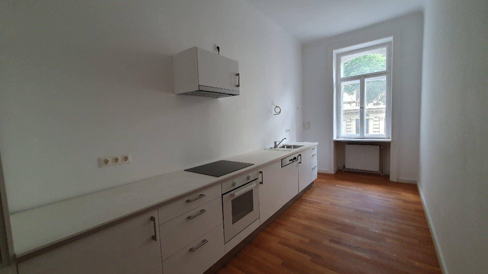 Moderne Einbauküche mit weißen Schränken, Kochfeld und Ofen, bereit zur Nutzung.