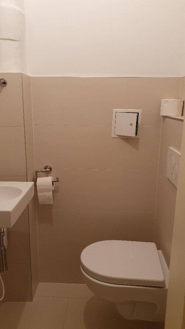 Kompaktes Gäste-WC mit Wand-WC und beigefarbenen Fliesen, funktional und sauber.