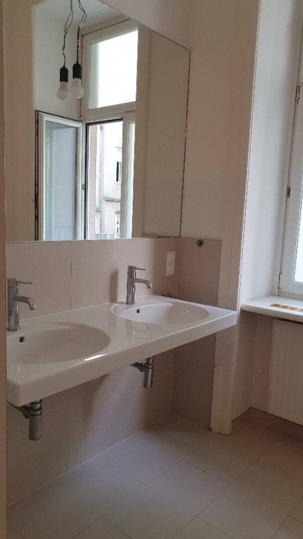 Modernes Badezimmer mit Doppelwaschbecken, großem Spiegel und Fenster für natürliches Licht.