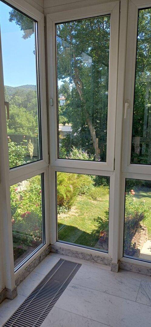 Erkerbereich im Wohnzimmer mit großen Fenstern, die einen weiten Blick in den Garten ermöglichen.