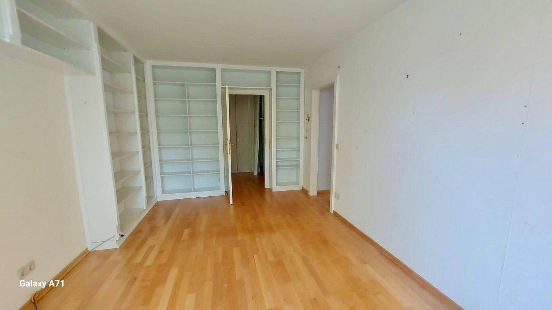 Raum mit hellem Holzparkett und raumhohen Einbauregalen, ideal als Büro oder Bibliothek.