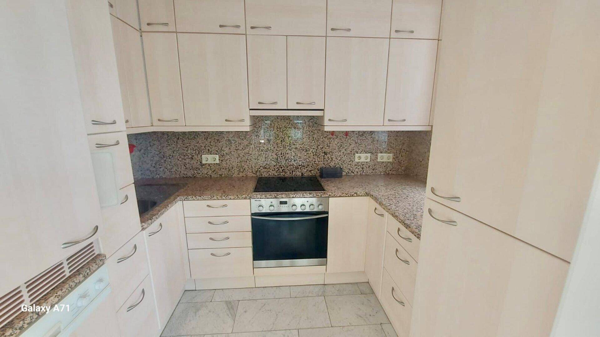 Einbauküche mit hellen Holzfronten, Granitarbeitsplatten und integrierten Geräten.