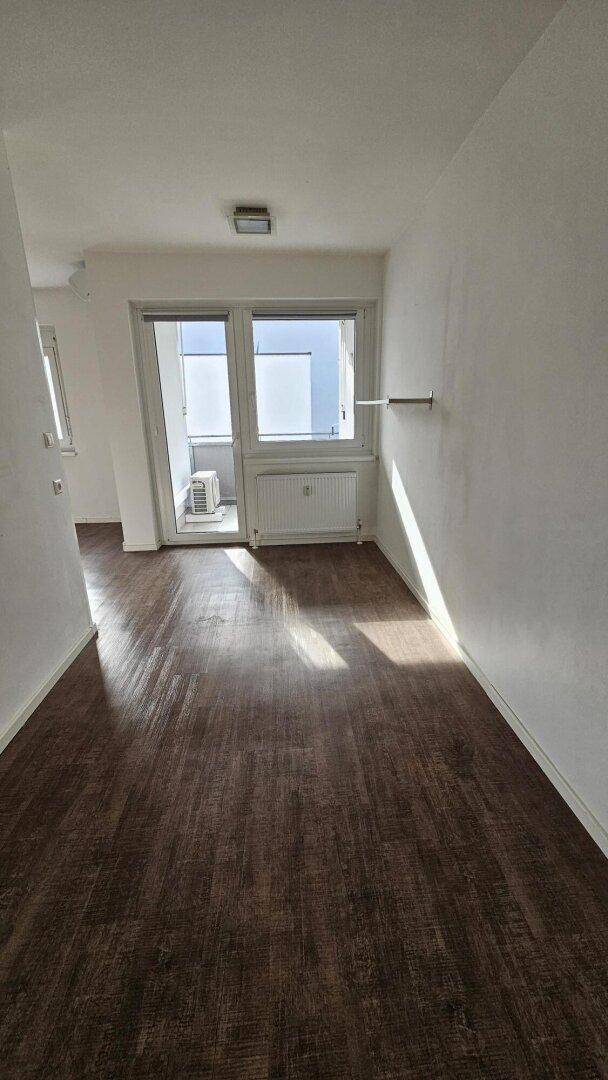 Heller Flur mit Laminatboden und Zugang zu einem kleinen Balkon.