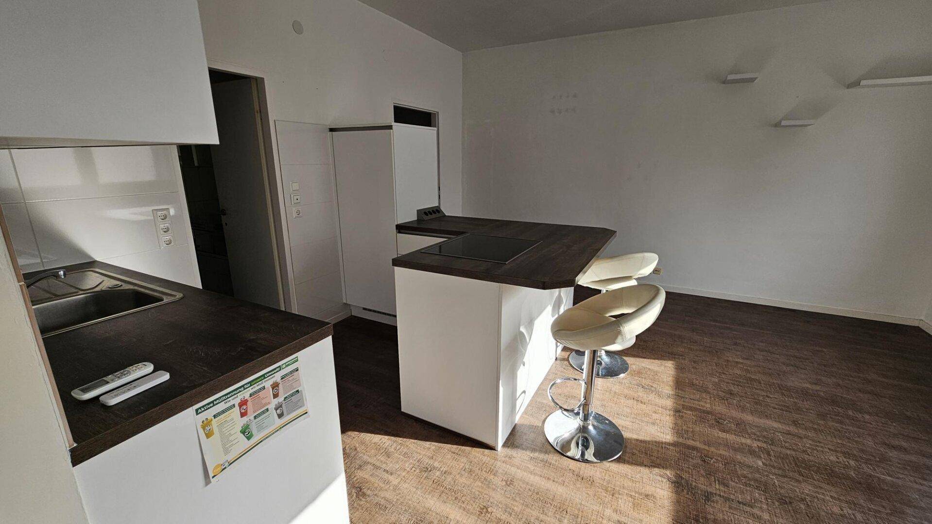 Funktionale Küche mit Bartheke, integriertem Kühlschrank und Laminatboden.