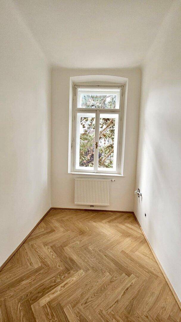Kleines, helles Zimmer mit Fischgrätparkett und einem Fenster, ideal als Schlaf- oder Arbeitszimmer.