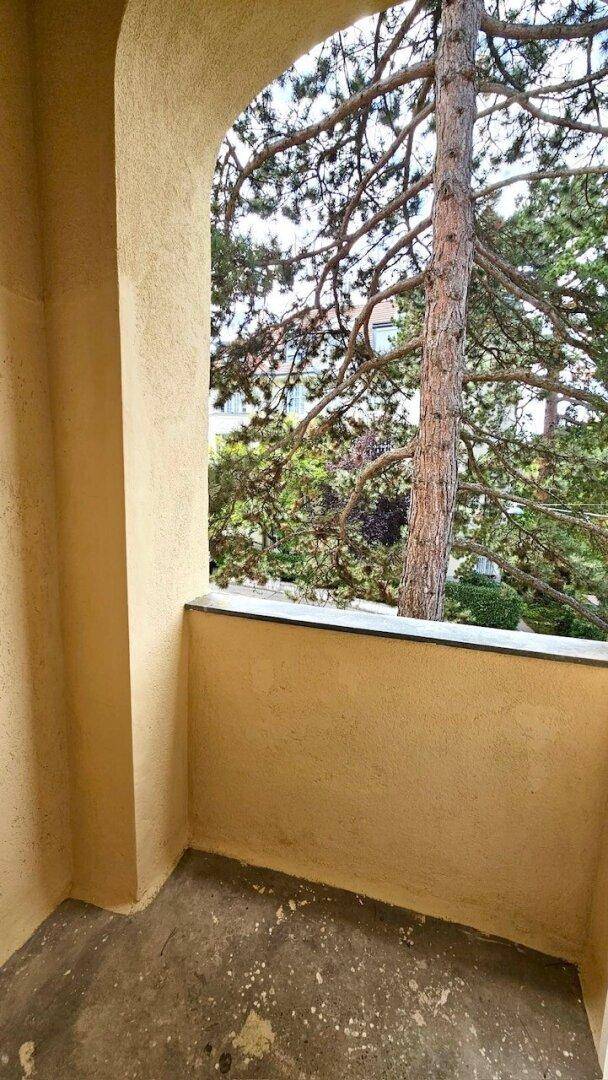 Gemütliche Loggia mit Blick auf einen großen Baum, ideal für entspannte Stunden im Freien.