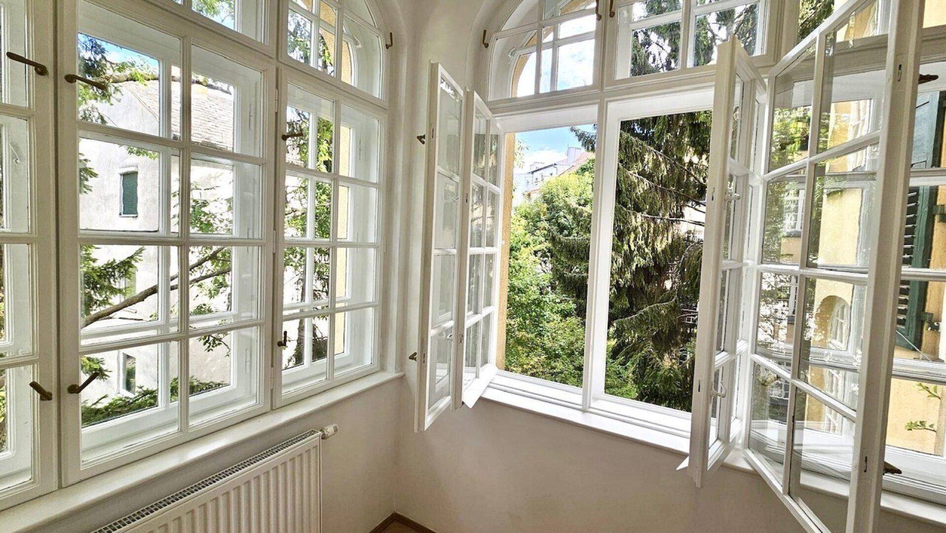 Geöffnete Sprossenfenster lassen frische Luft herein und bieten einen angenehmen Blick ins Grüne.
