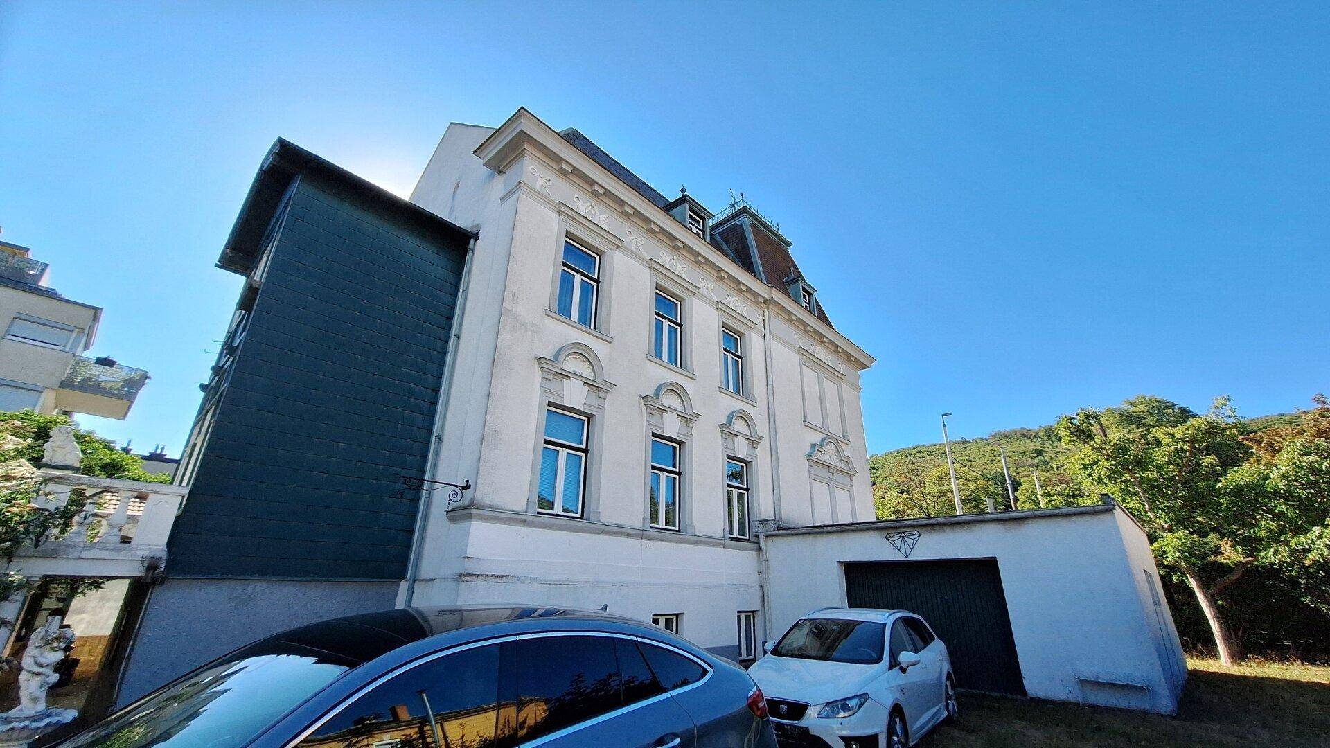 Seitenansicht des Gebäudes mit integrierter Garage und Parkmöglichkeiten im Freien.