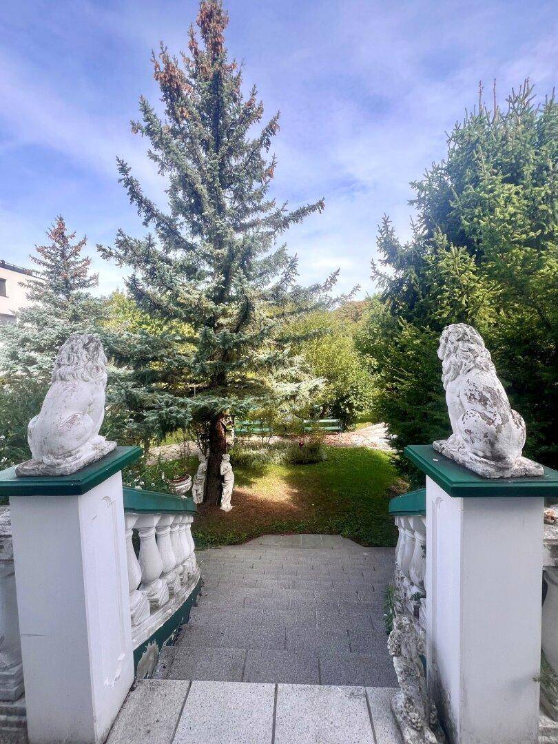 Historische Steintreppe mit Löwenstatuen führt hinab in den weitläufigen Gartenbereich.