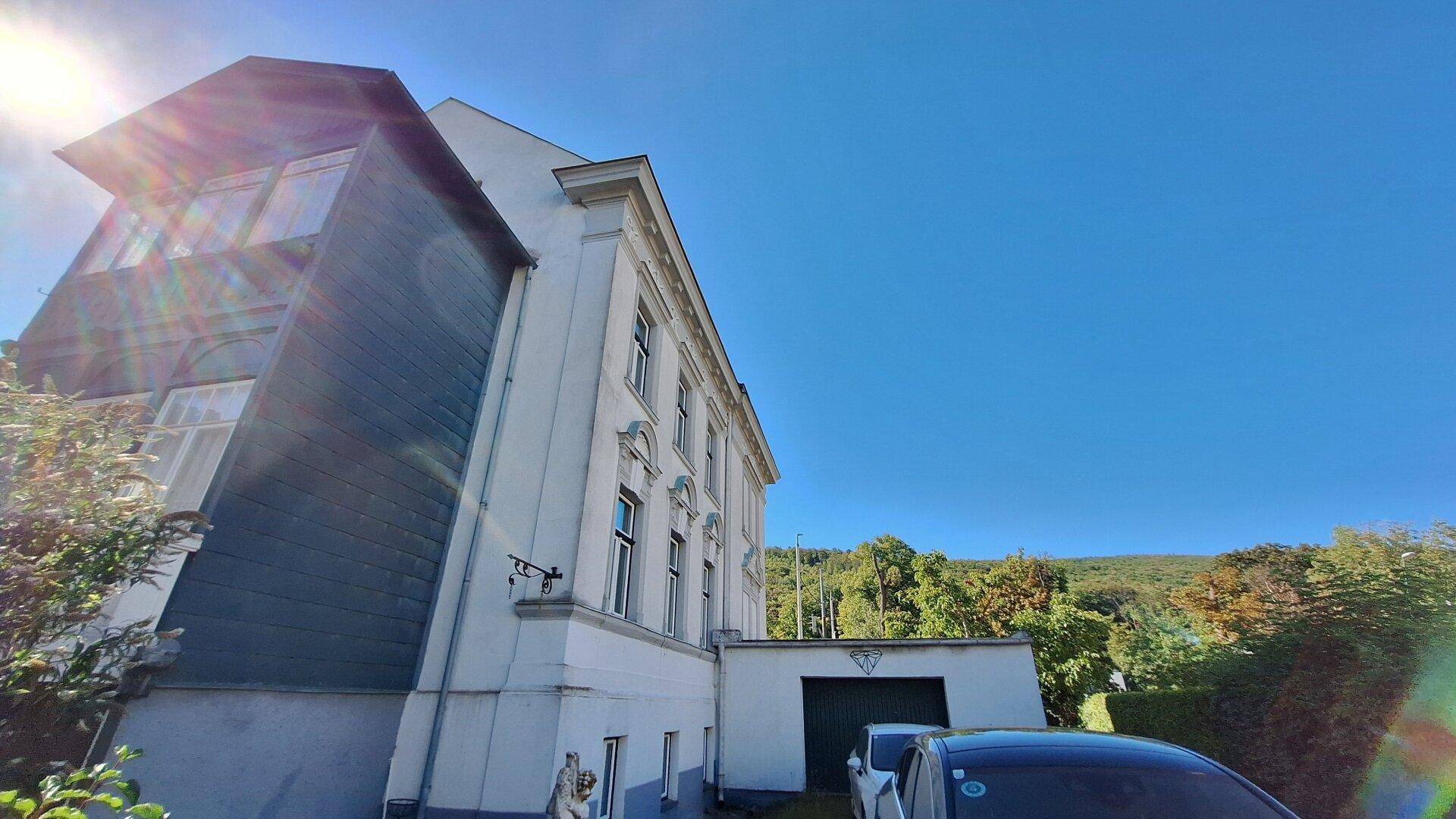 Gebäudeseite mit dunkler Fassadenverkleidung und der Zufahrt zur Garage unter blauem Himmel.