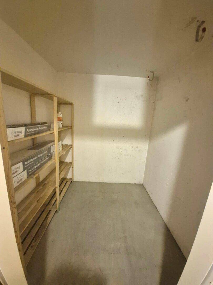 Einfacher Abstellraum im Keller mit Betonboden und Holzregalen für zusätzlichen Stauraum.
