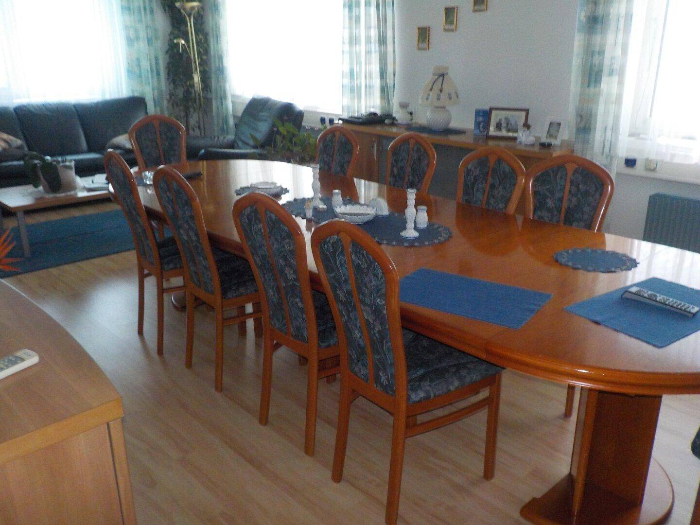 Geräumiger Essbereich mit großem Holztisch und passenden Stühlen, angrenzend an einen Wohnbereich.