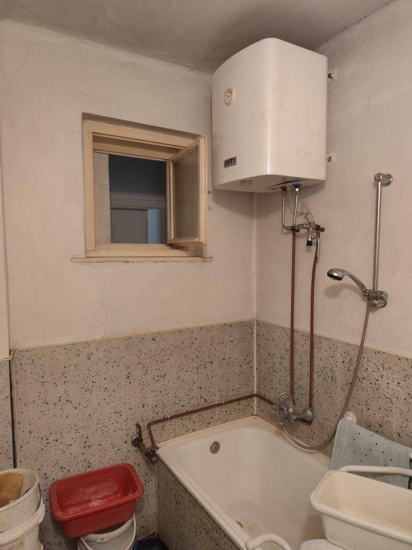 Funktionales Badezimmer mit Badewanne, Warmwasserboiler und kleinem Fenster.