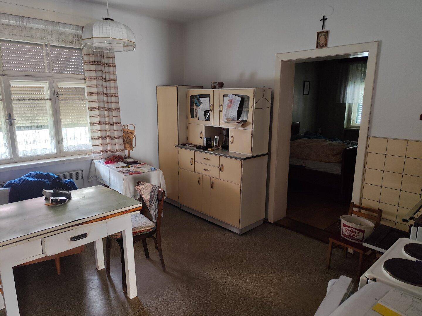 Rustikale Küche mit traditionellem Schrank, Esstisch und Blick in ein angrenzendes Schlafzimmer.