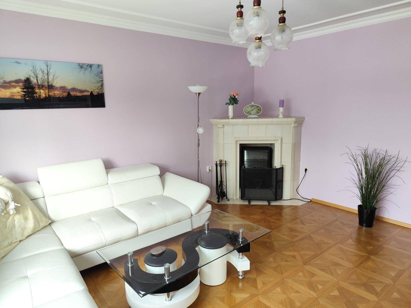 Gemütliches Wohnzimmer mit hellem Sofa, Parkettboden und einem dekorativen Kamin.