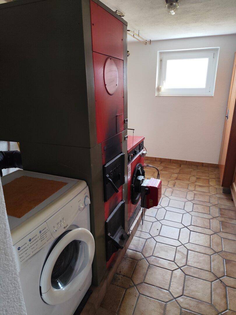 Hauswirtschaftsraum mit Heizungsanlage, Waschmaschine und Fliesenboden.