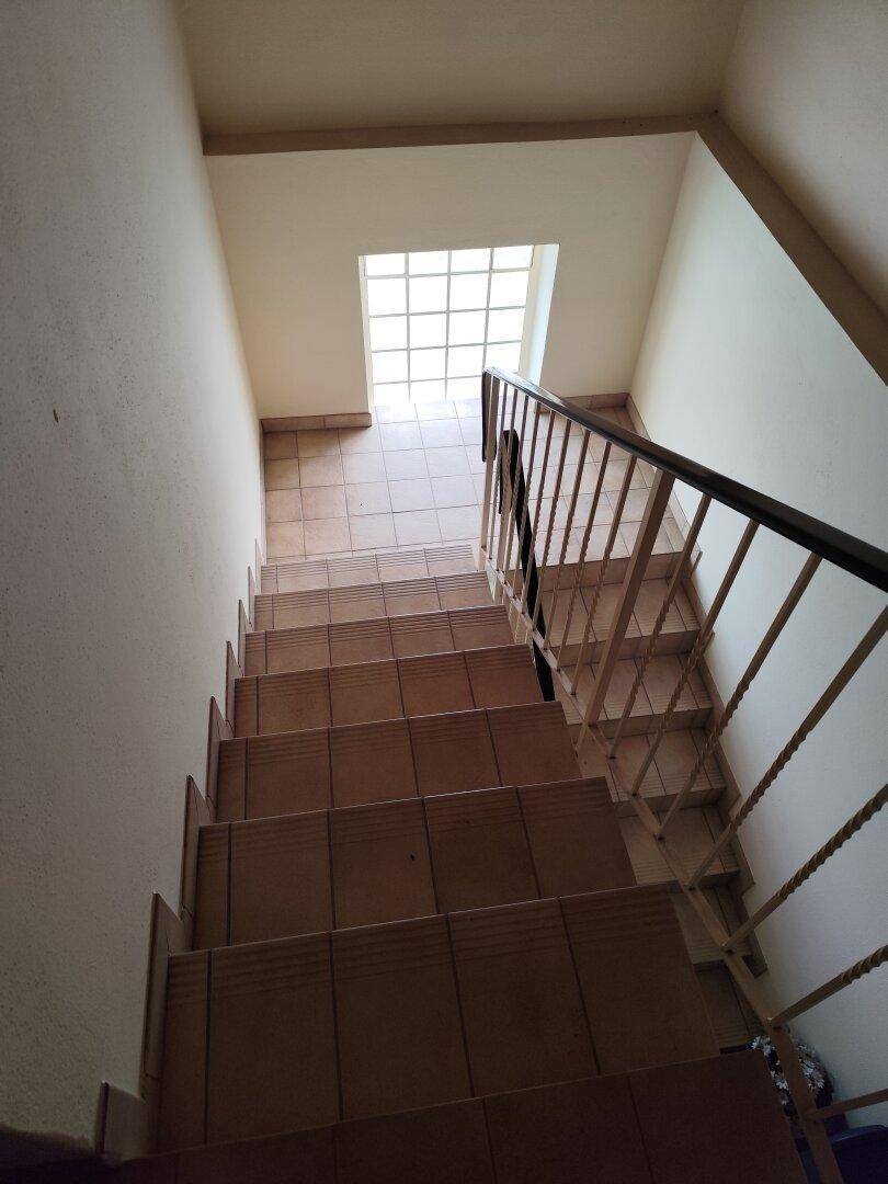 Treppenhaus von oben gesehen mit Fliesenstufen und einem Oberlicht für natürliches Licht.