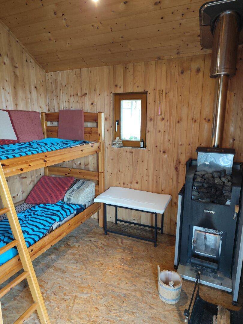 Rustikale Sauna mit Holzverkleidung, Etagenbett und traditionellem Saunaofen.