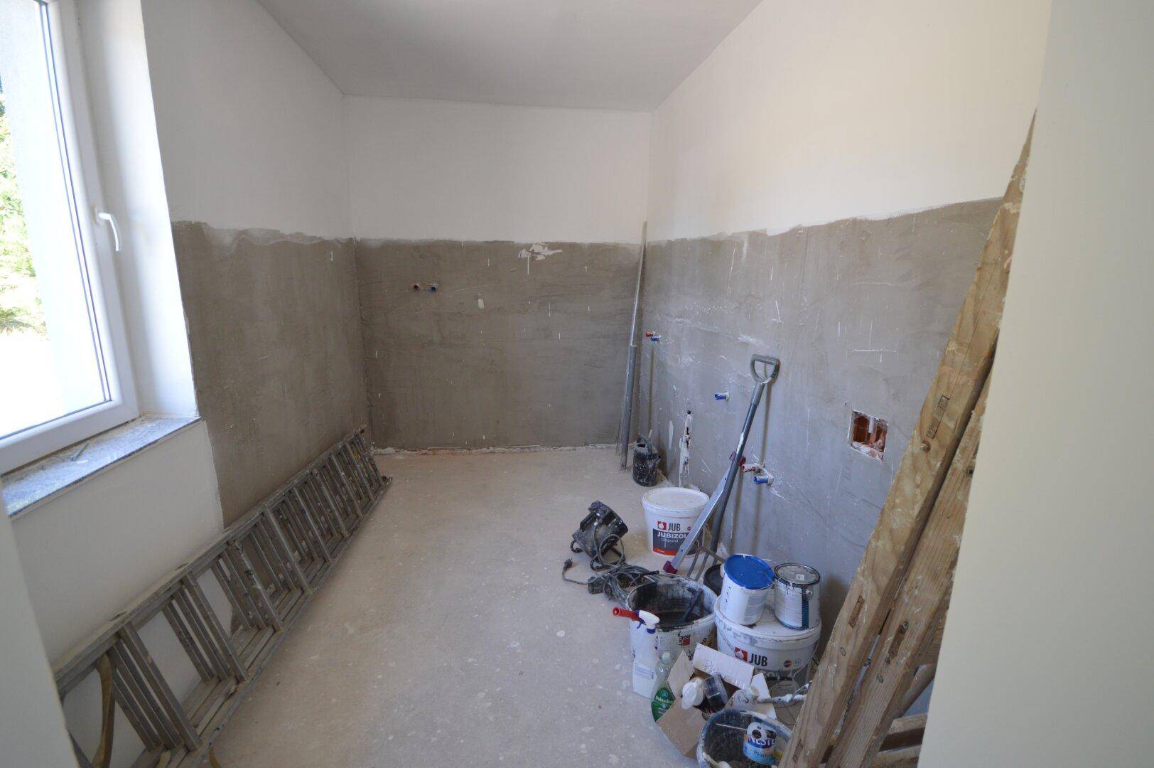 Rohbau eines Raumes mit Baugeräten und halbfertigen Wänden, bereit für den weiteren Ausbau.