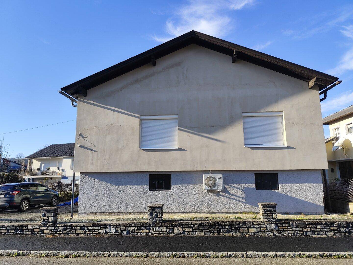 Vorderansicht des Hauses mit Rollläden an den Fenstern und einer Klimaanlage.