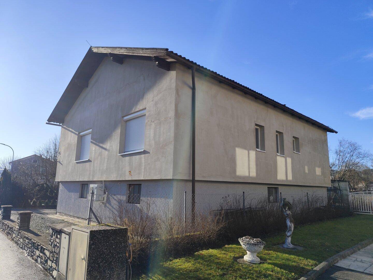 Seitenansicht des Hauses mit Fenstern und einem kleinen Vorgartenbereich.