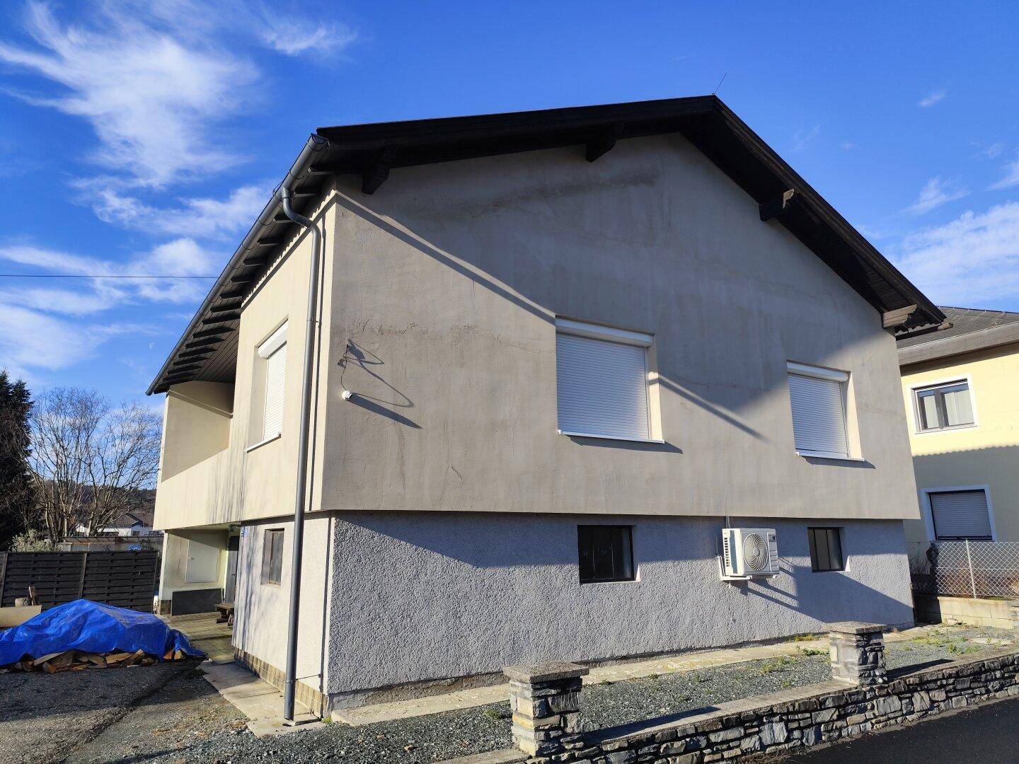 Ansicht der Hausfassade mit Rollläden an den Fenstern und einer Klimaanlage an der Wand.