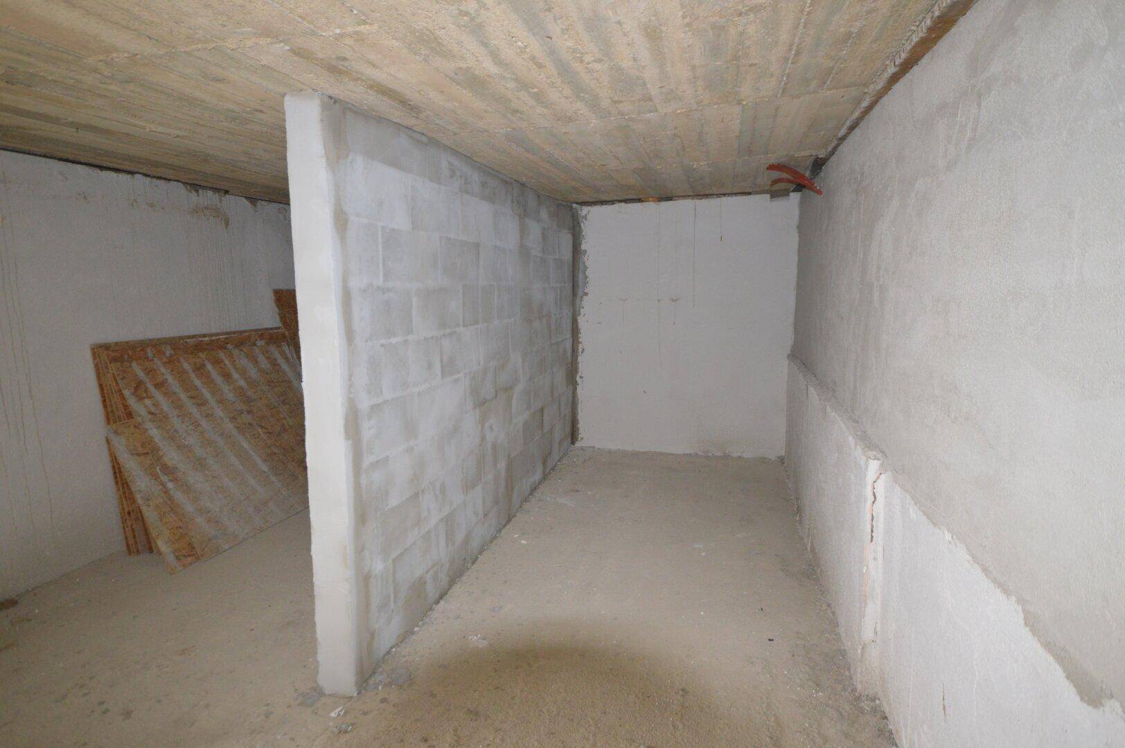 Unfertiger Kellerraum mit Betonwänden und -decke, ideal als Lagerfläche.