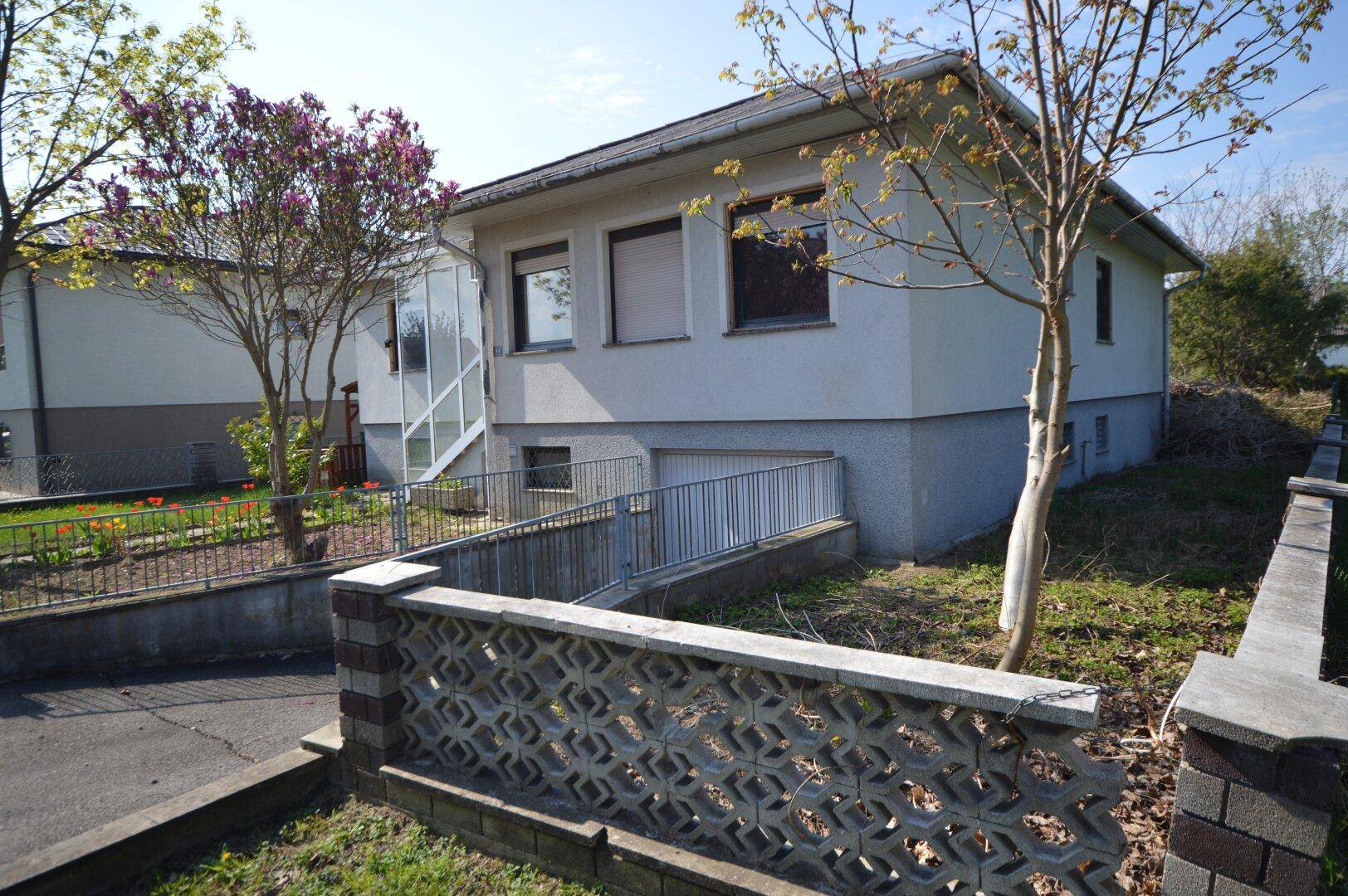 Seitenansicht des Hauses mit Zufahrt zur Tiefgarage oder Keller und einem kleinen Gartenbereich.