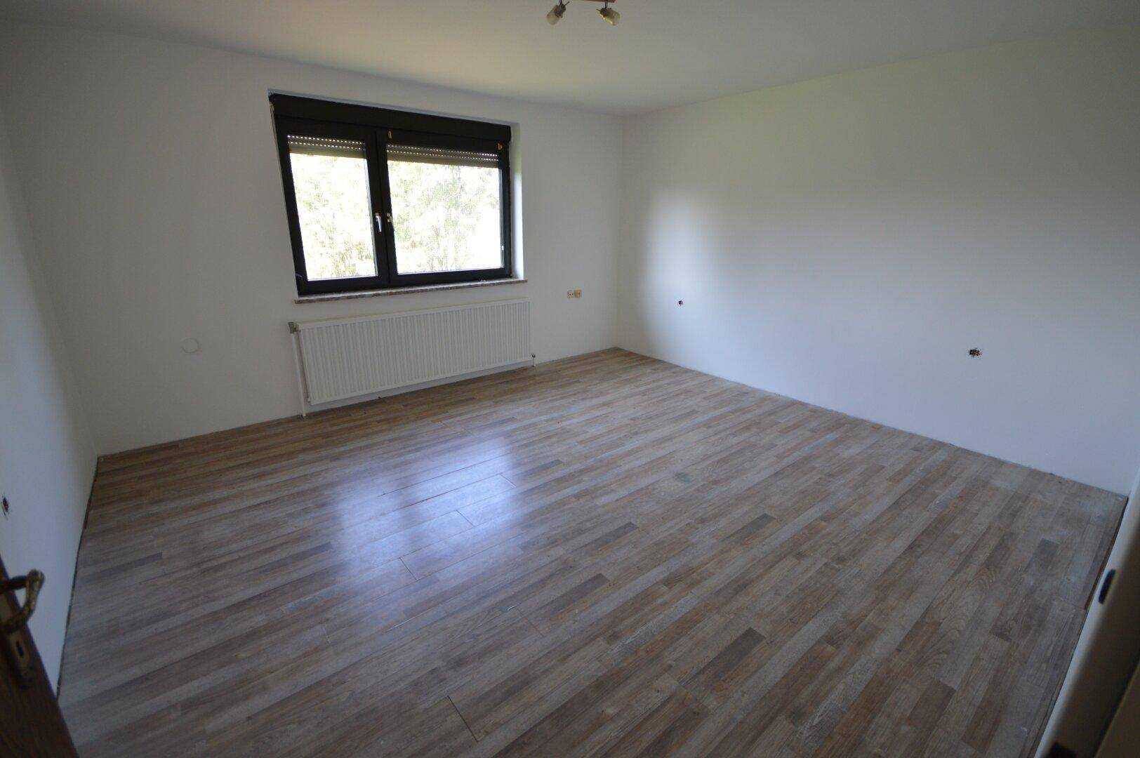 Geräumiges Schlafzimmer mit Laminatboden und einem großen Fenster für viel Helligkeit.