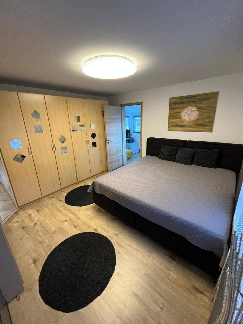 Geräumiges Schlafzimmer mit großem Doppelbett, hellen Holzschränken und dunklen Teppichen.