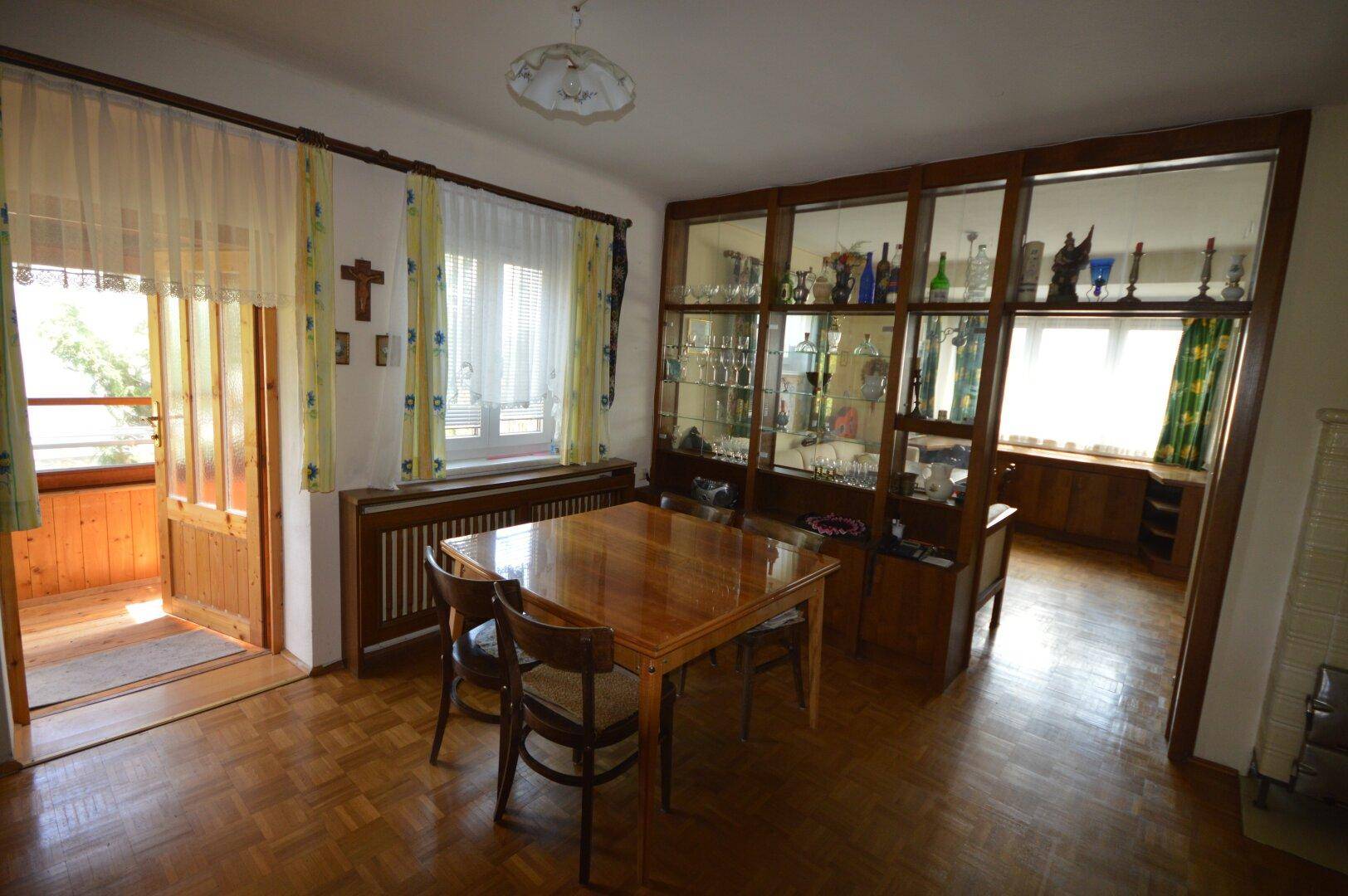 Gemütlicher Essbereich mit Parkettboden, Holzmöbeln und Zugang zum Balkon.