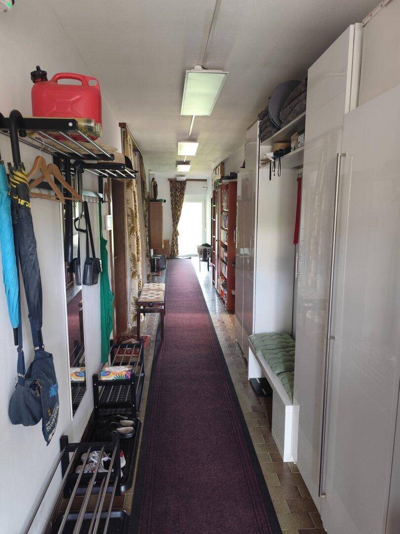 Langer Flur mit Teppichläufer, Garderobe und Schränken, führt durch das Haus.