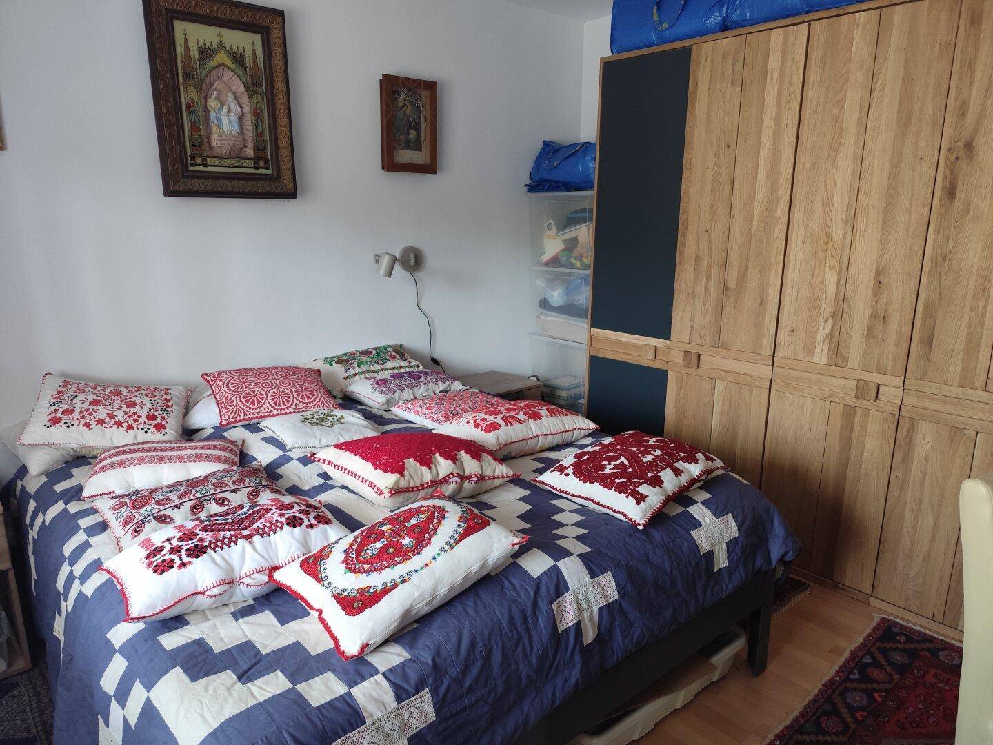 Schlafzimmer mit großem Bett, vielen Kissen und Holzschrank, strahlt Gemütlichkeit aus.