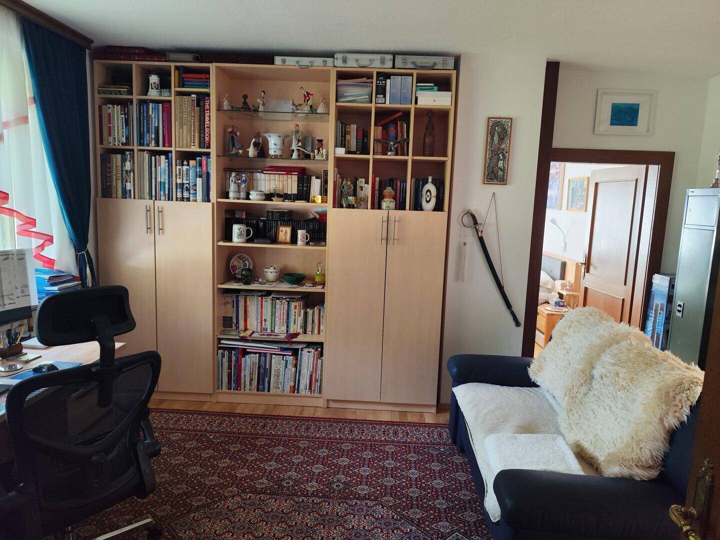 Arbeitszimmer mit Bücherregalen, Schreibtisch und bequemer Couch, ideal zum Lesen.