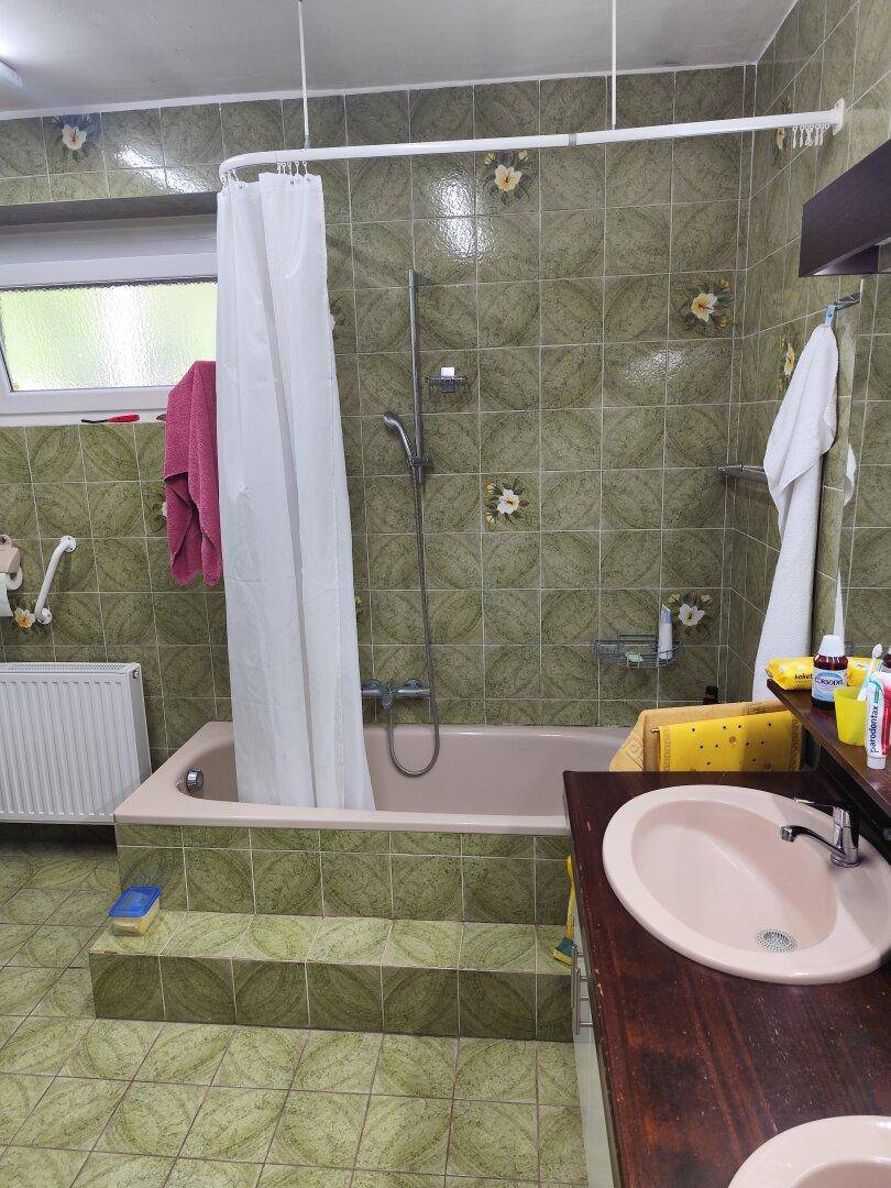 Badezimmer im Stil der 80er Jahre mit grünen Fliesen, Badewanne und Waschbecken.