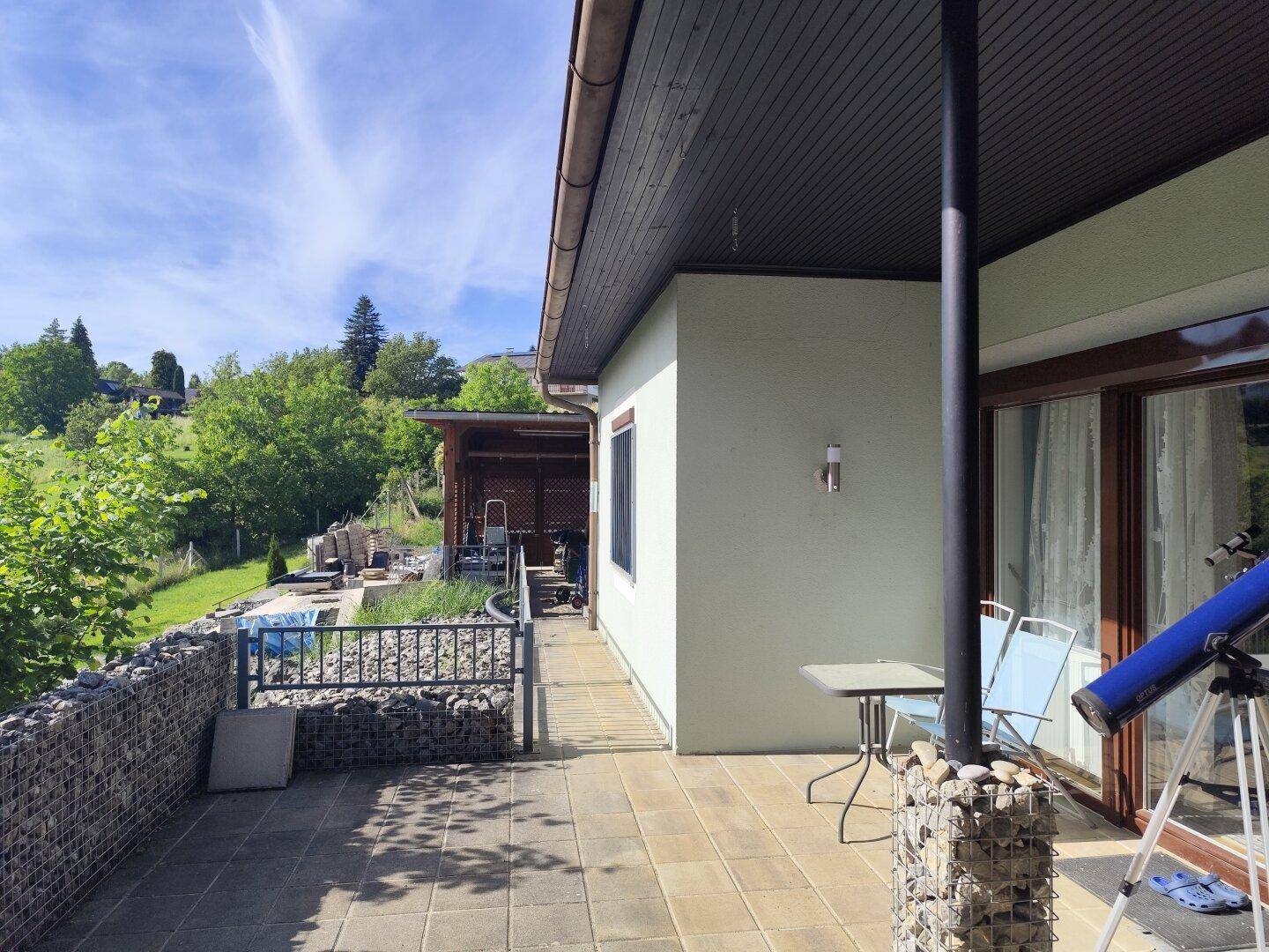 Gedeckte Terrasse mit Steinmauern und Blick ins Grüne, ideal für Entspannung im Freien.