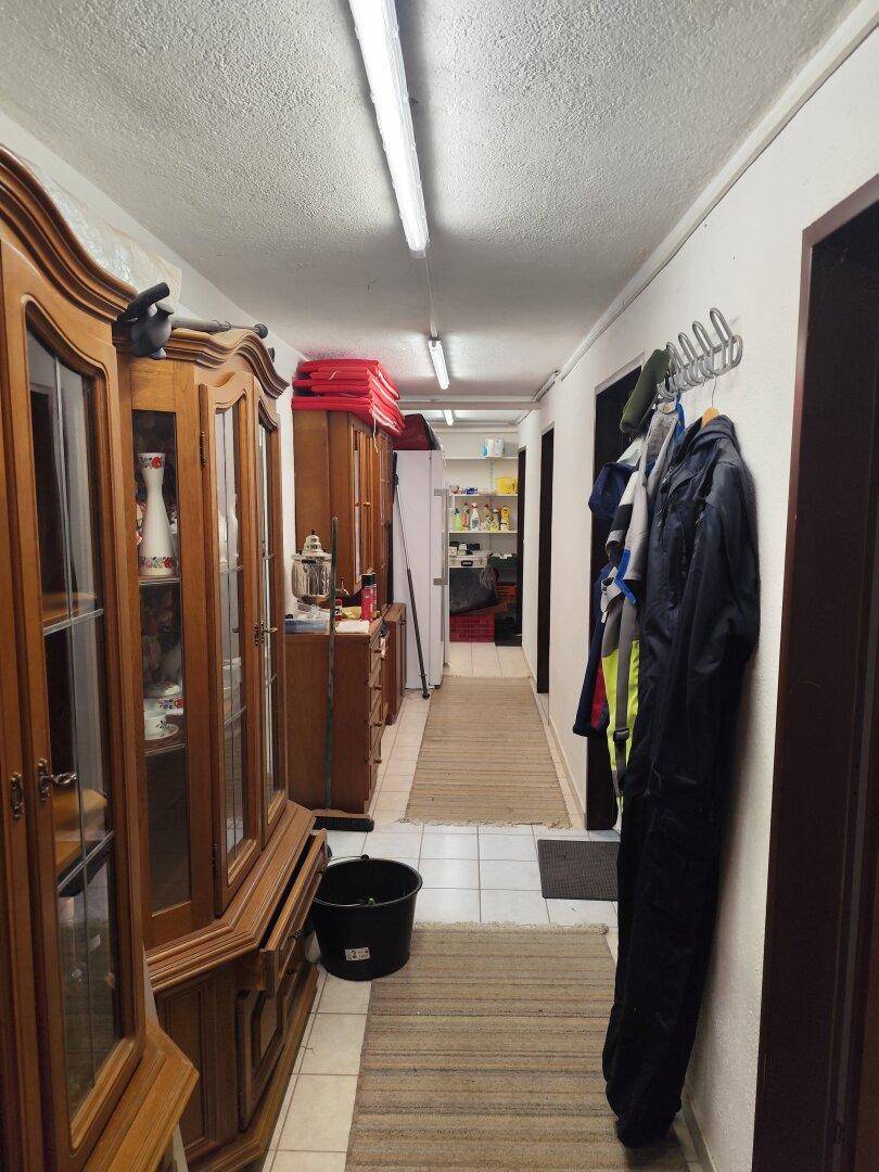 Langer Flur mit Holzschränken, Garderobe und Fliesenboden, führt zu weiteren Räumen.