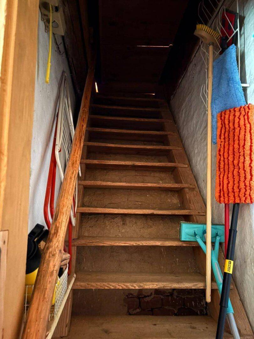 Rustikale Holztreppe führt in ein oberes Stockwerk, umgeben von weiß getünchten Wänden.