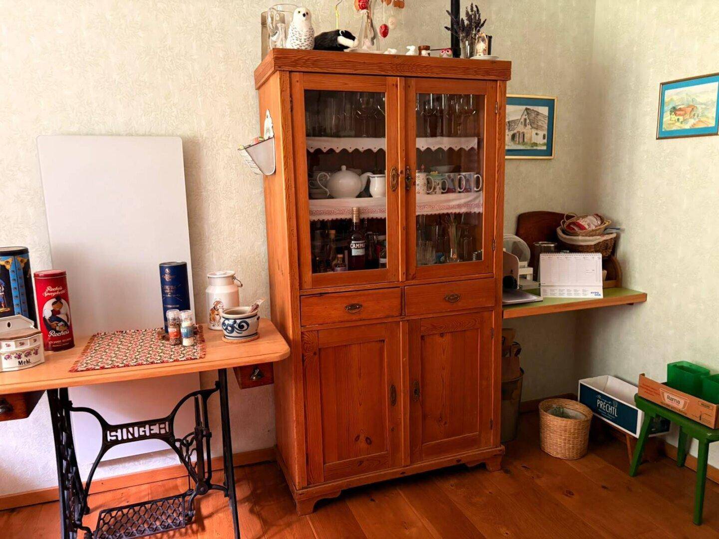 Raum mit Holzschrank, Nähmaschine und traditioneller Tapete.