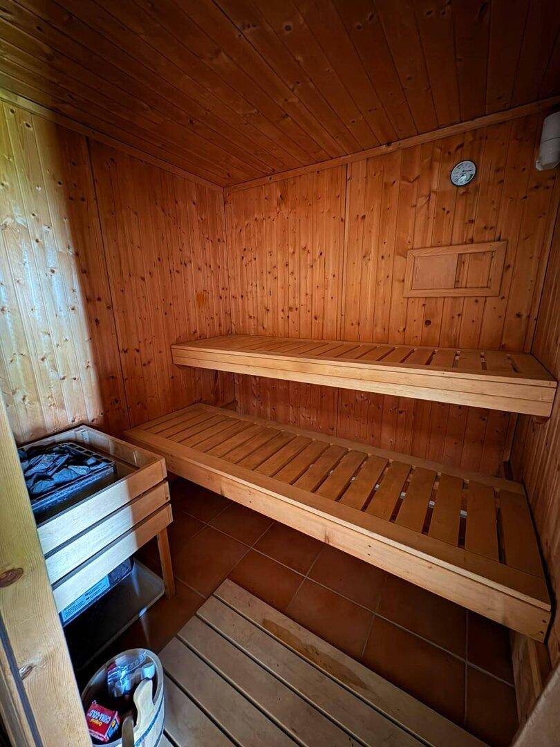 Traditionelle Holzsauna mit zwei Liegeebenen und Saunaofen für Entspannung.