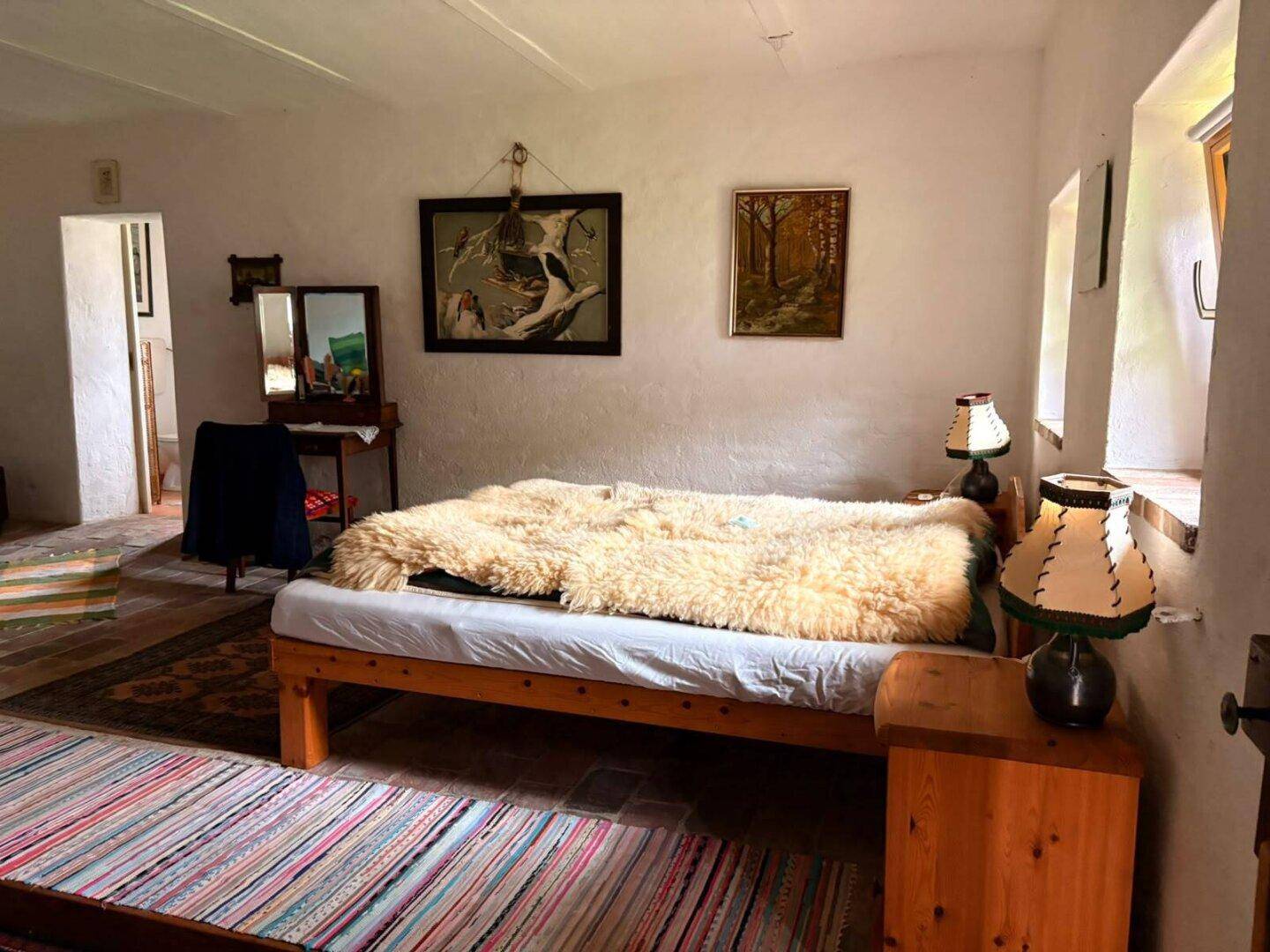 Gemütliches Schlafzimmer mit Holzbett, flauschiger Decke und traditionellen Teppichen.