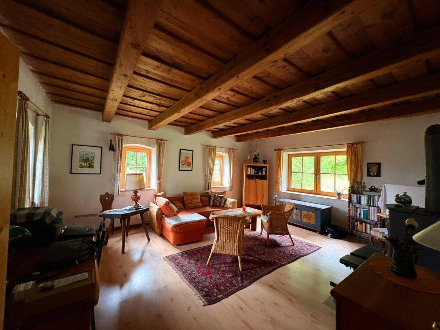 Geräumiges Wohnzimmer mit Holzbalkendecke, hellen Holzböden und gemütlicher Sitzecke.