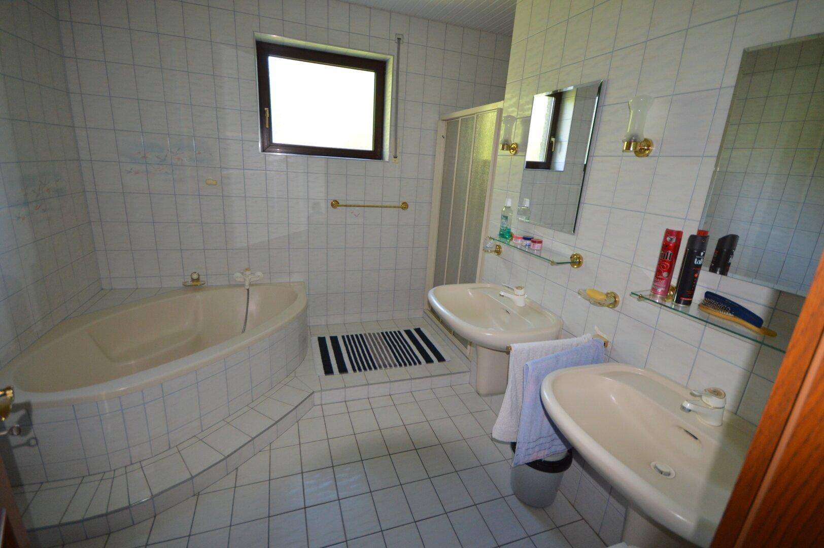 Badezimmer mit Badewanne, zwei Waschbecken und weißen Fliesen im klassischen Stil.