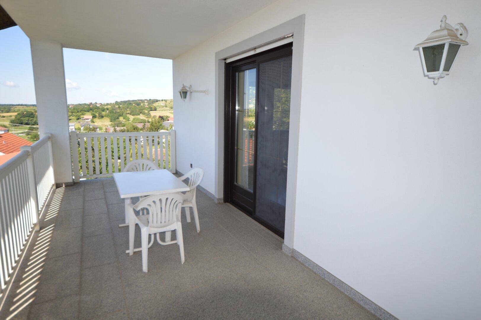 Heller Balkon mit Gartenmöbeln und weitem Blick über die umliegende Landschaft.