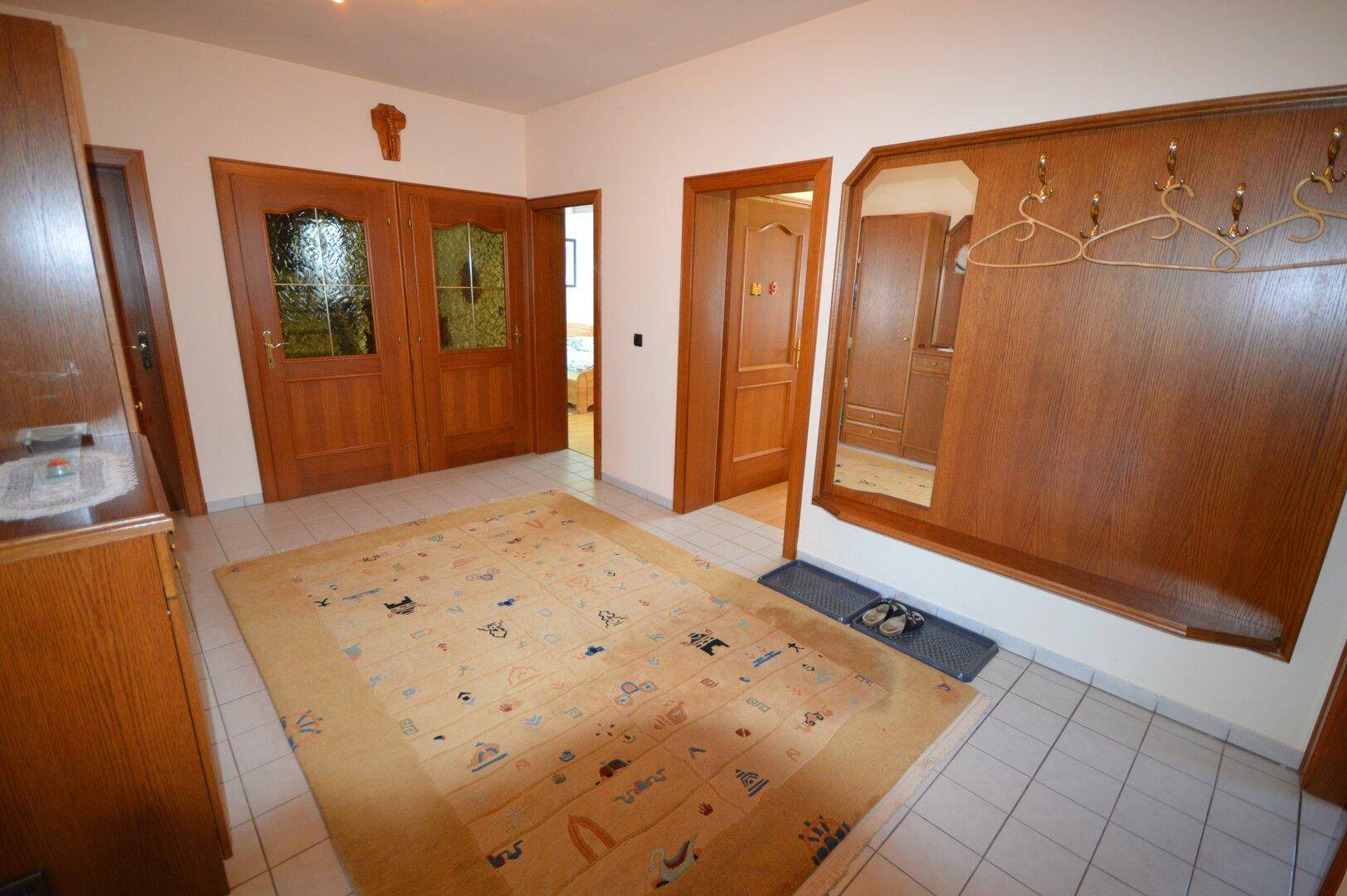 Geräumiger Flur mit Fliesenboden, Holzmöbeln und einer Garderobe.