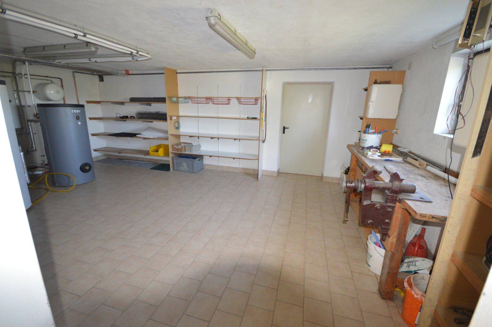 Geräumiger Hauswirtschaftsraum im Keller mit Regalen und Werkbank.