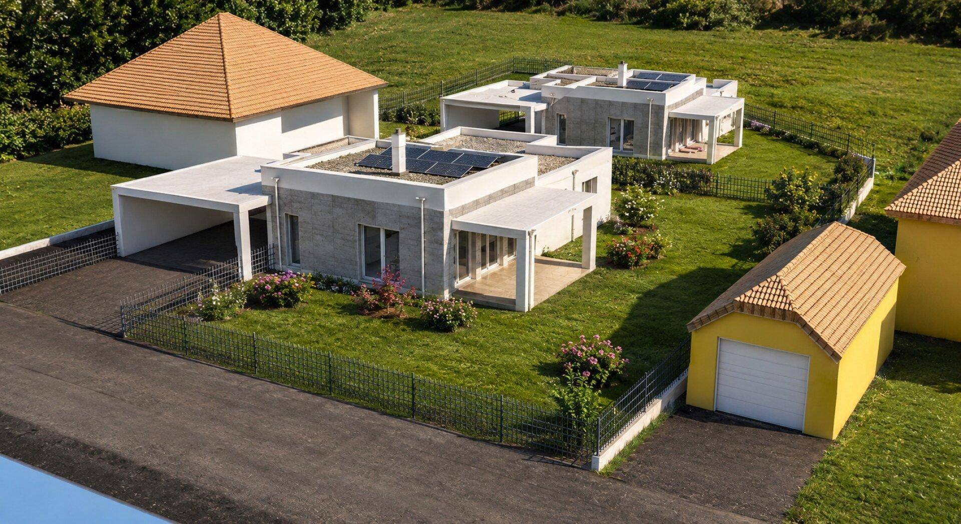 Moderne Häuser mit Flachdächern, integrierten Carports und gepflegten Gärten in einer ruhigen Wohngegend, von oben.