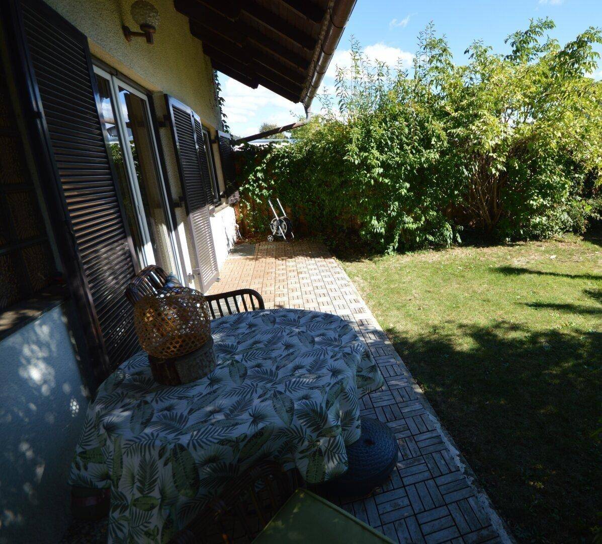 Sonnige Terrasse mit Holzbodenfliesen und Gartenblick, ideal für entspannte Stunden im Freien.